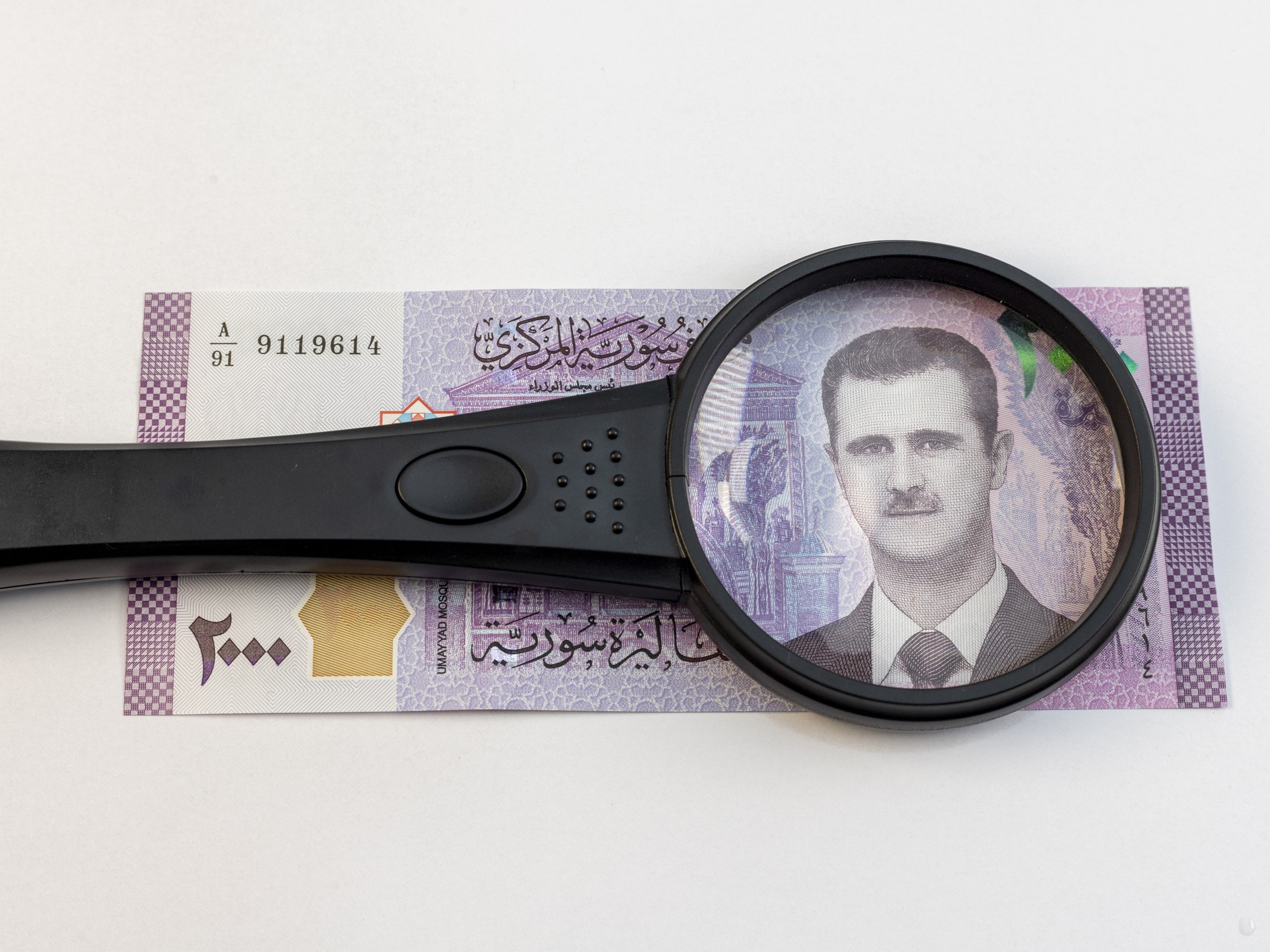 Magnifying glass over Syrian currency